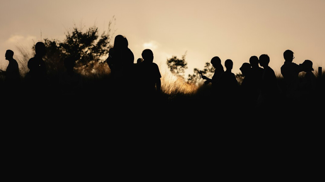 Anonymous crowd of people seen as silhouettes from a distance